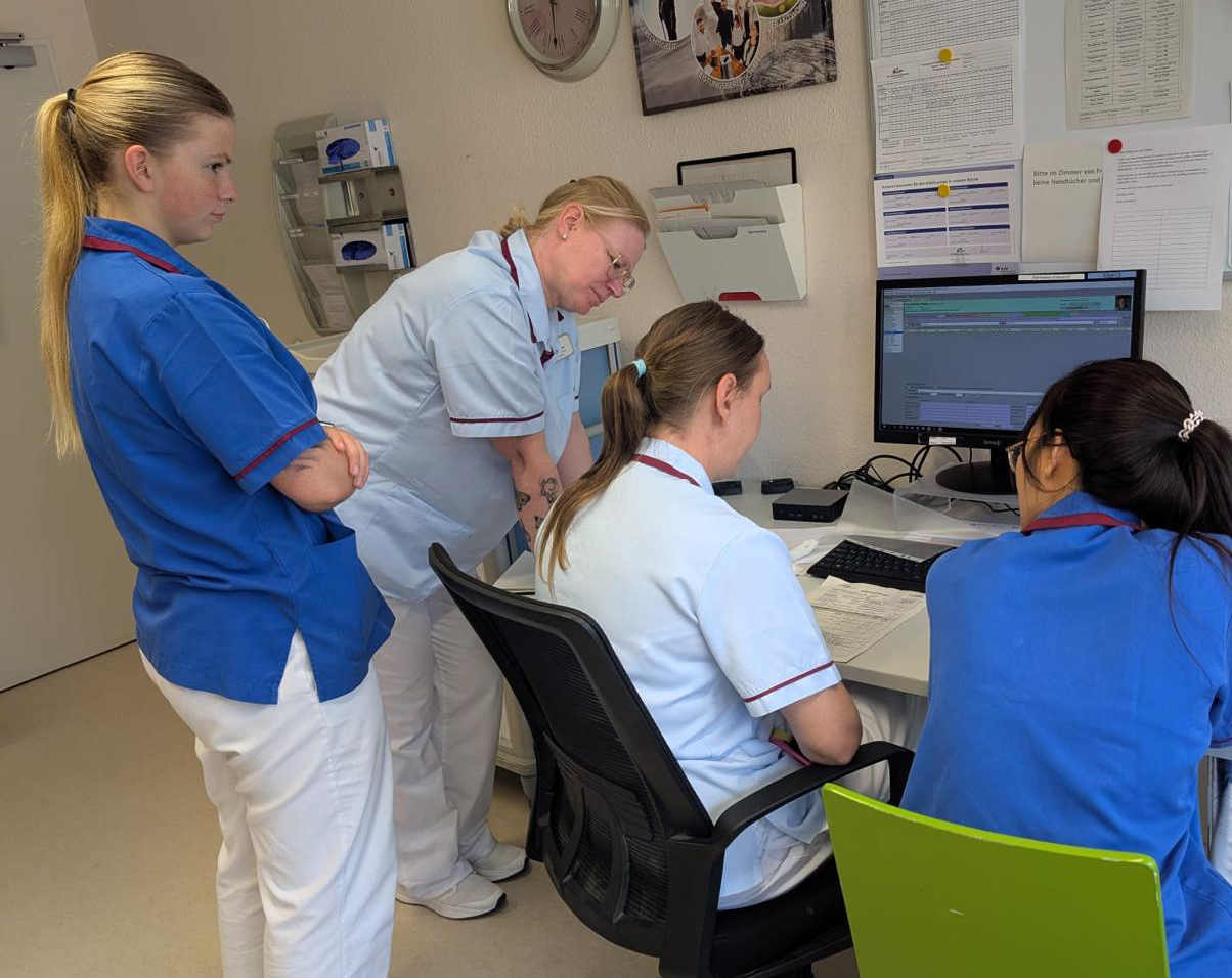 Zwei Auszubildende bekommen von der Praxisanleitung etwas erklärt.